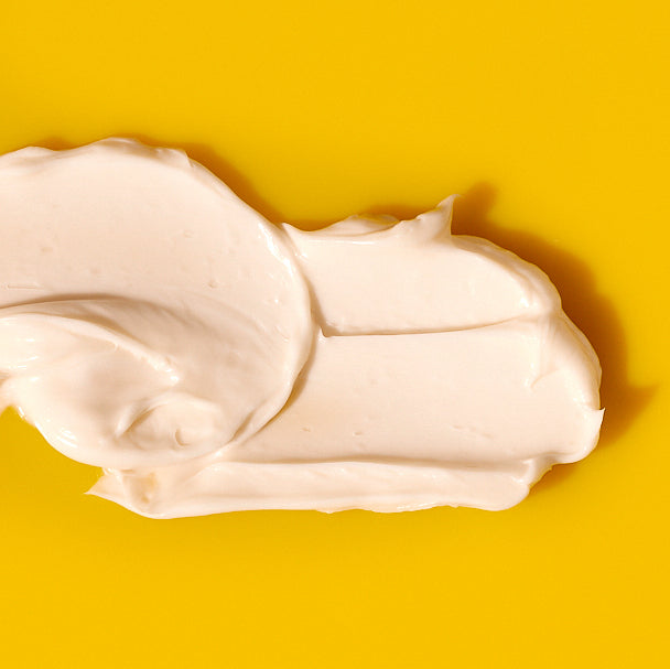 Dollop of white cream on a bright yellow background.