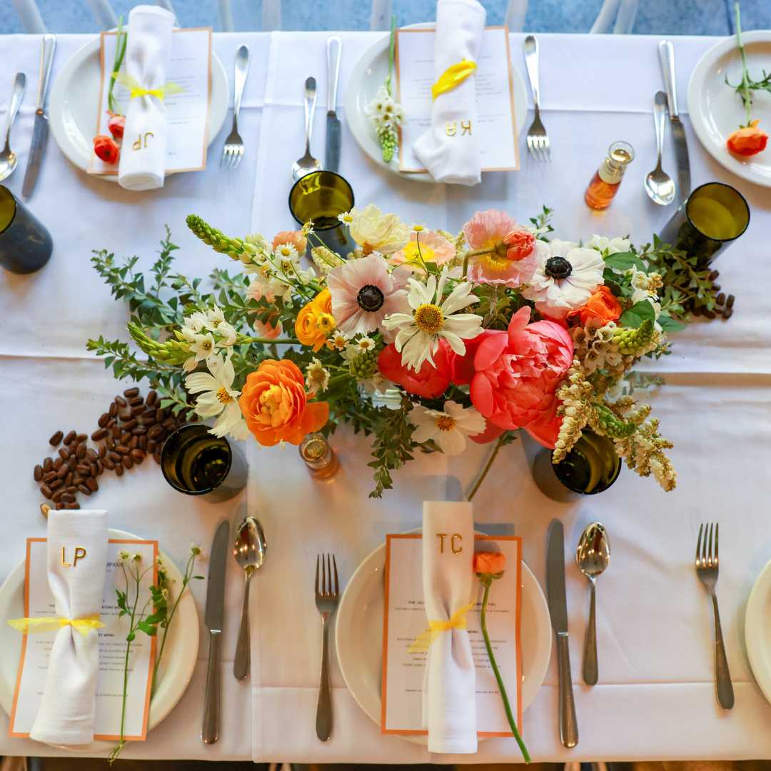 Elegant dining table set with a colorful flower centerpiece, place settings, and personalized menus.