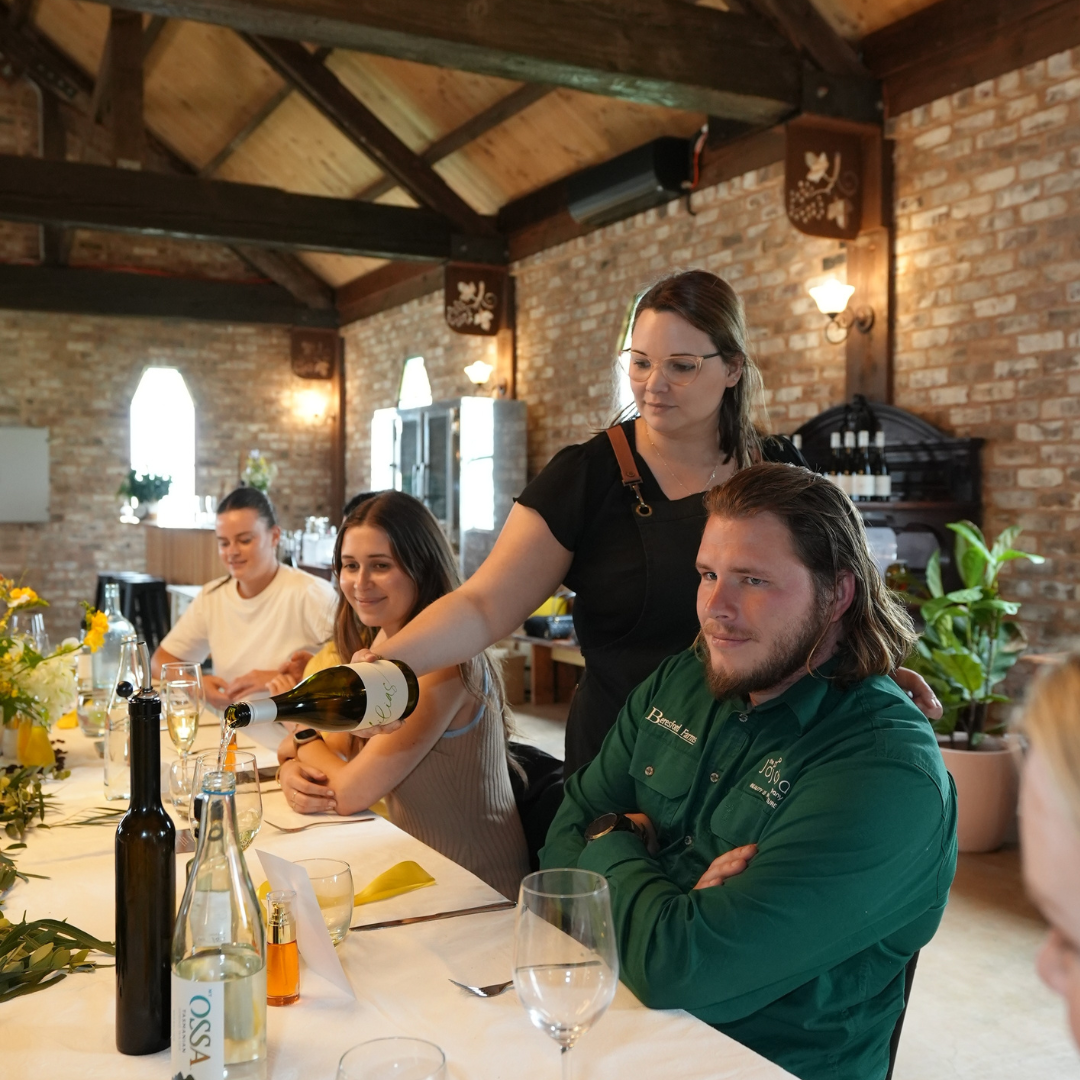 A server pouring wine at a table in a rustic brick-walled dining room.